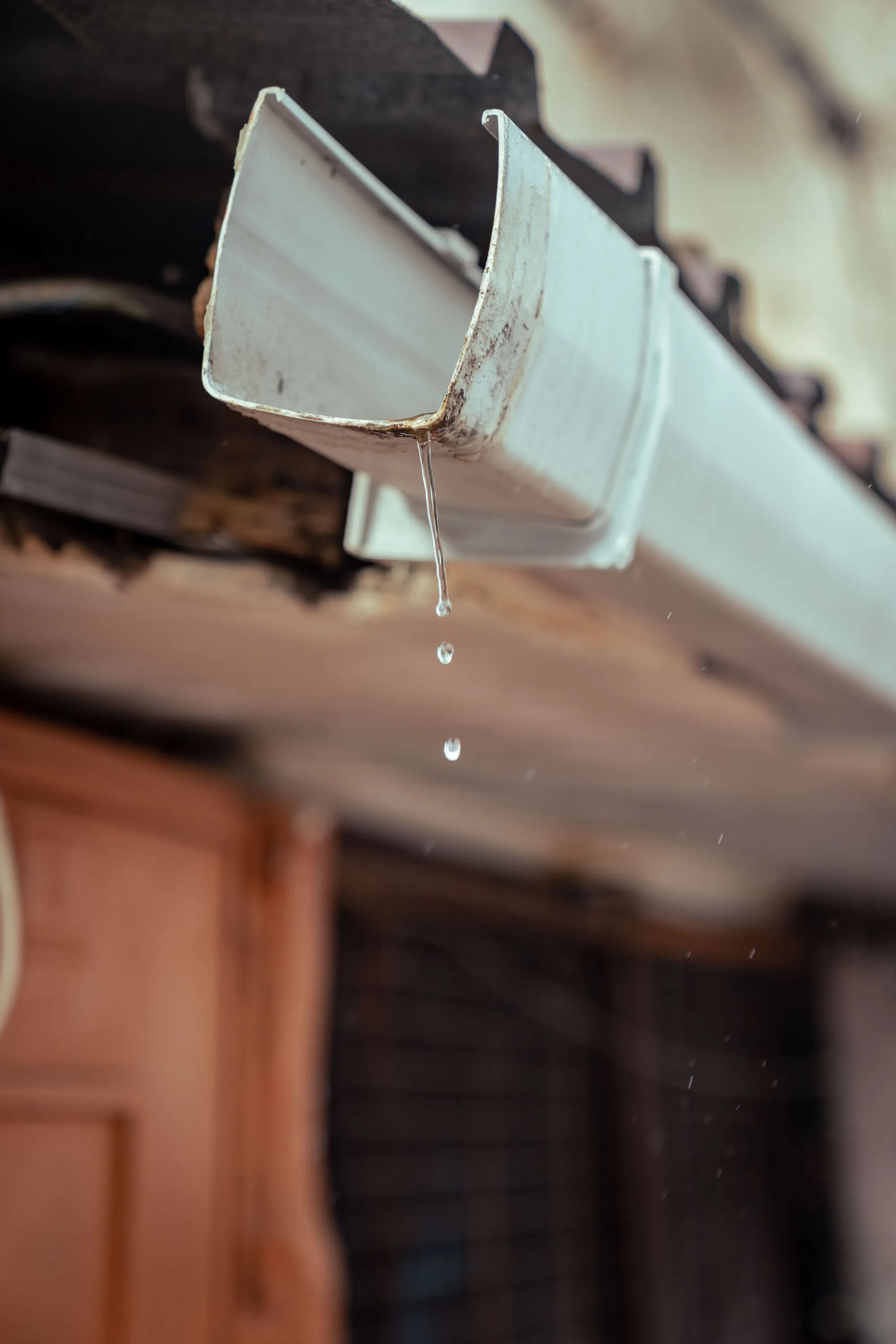 Rainwater running off the end of a gutter at the eaves