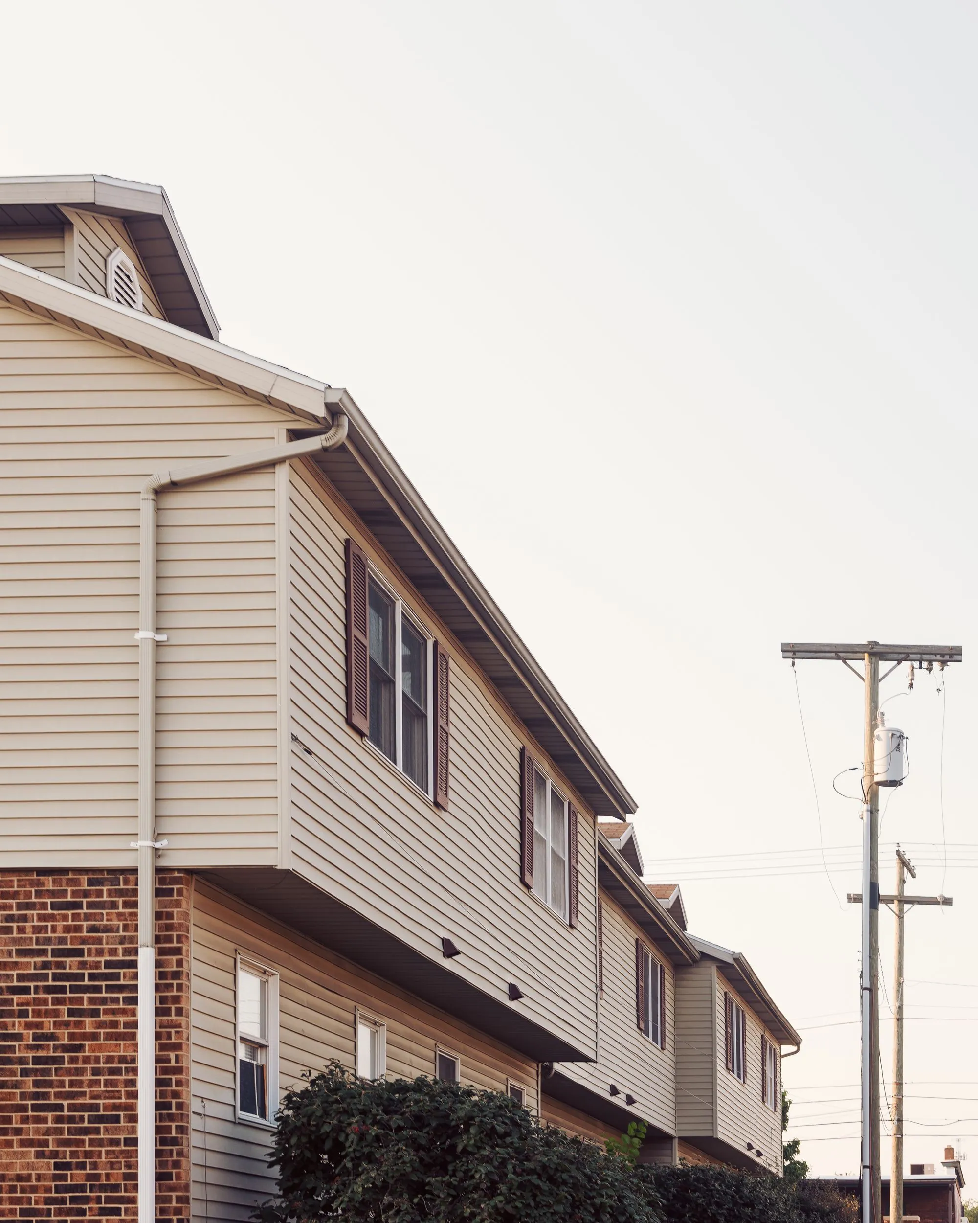 The side of a two-storey house with siding and a shingled roof