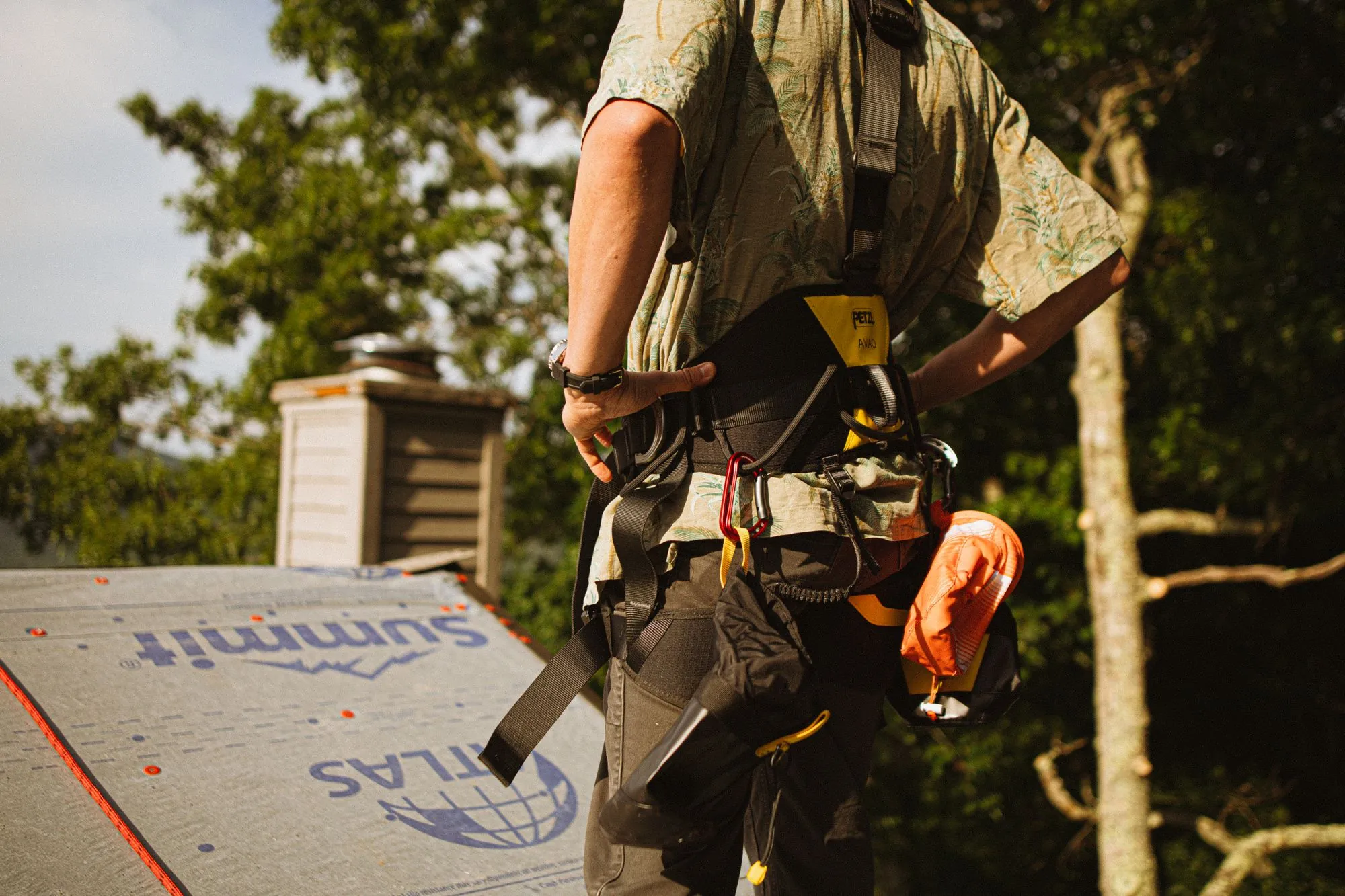 A roofer in a harness standing on a deck laid with underlayment